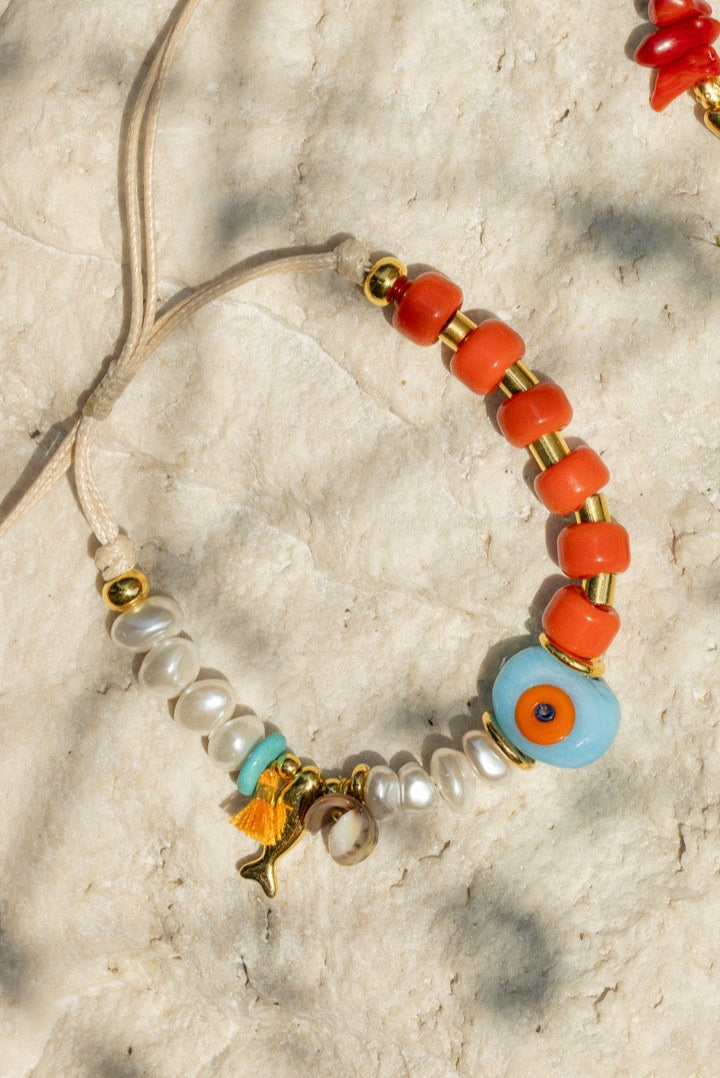 Colorful beaded jewelry with charms on a textured surface